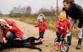 Happy family enjoying quality time outdoors with kids and dog in countryside.